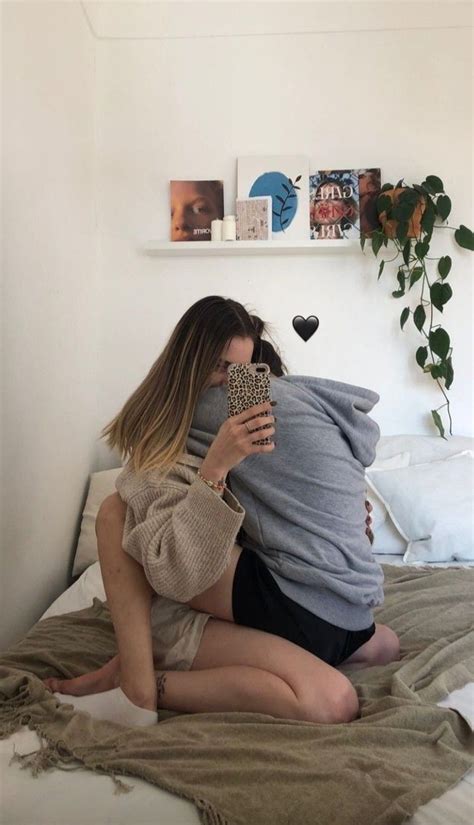 A Woman Sitting On Top Of A Bed Holding A Cell Phone