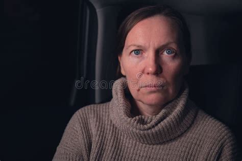 Low Key Portrait Of Serious Caucasian Mid Adult Woman At Car Back Seat