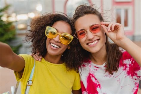 Retrato Colorido De Felizes Amigas Jovens Sorrindo Sentadas Na Rua