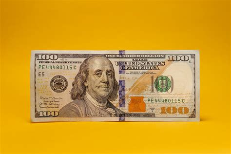 A one hundred dollar bill on a yellow background photo – Free Man Image