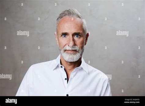 Mature Man With Gray Hair And Beard Standing In Front Of Grey