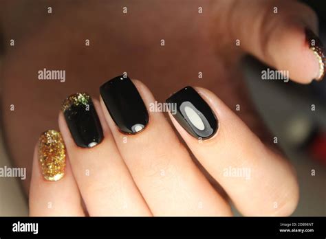 Evening manicure design in black and gold color Stock Photo - Alamy