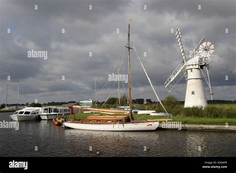 Thurne Dyke windmill on the River Thurne, Norfolk Broads, Englanda yacht is moored at the river ...