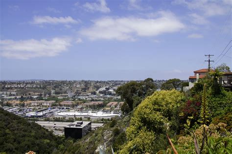 A View Of The City From Atop A Hill With Lots Of Trees And Bushes In