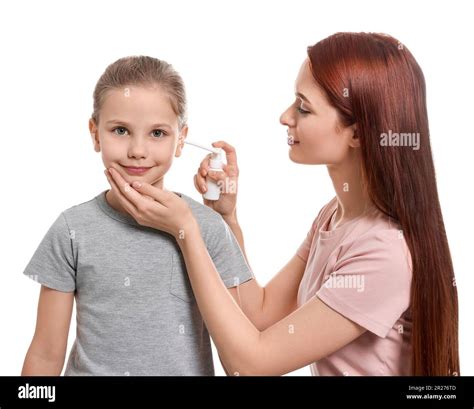 Mother Spraying Medication Into Daughters Ear On White Background