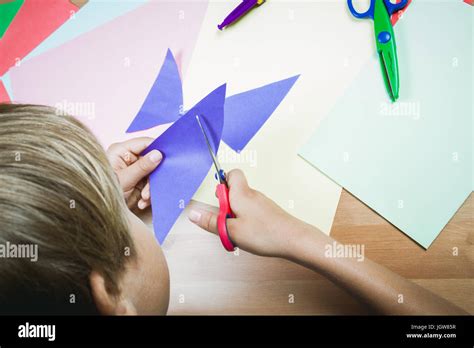 Boy Cutting Colored Paper With Scissors At The Table Stock Photo Alamy