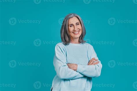 Mature Beautiful Woman Looking At Camera And Smiling While Standing Against Blue Background