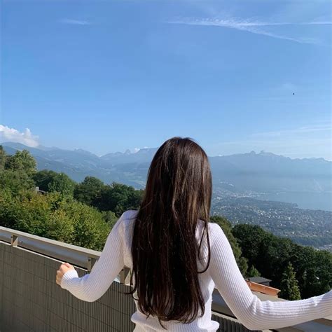 A Woman Standing On Top Of A Balcony Next To A Lush Green Hillside