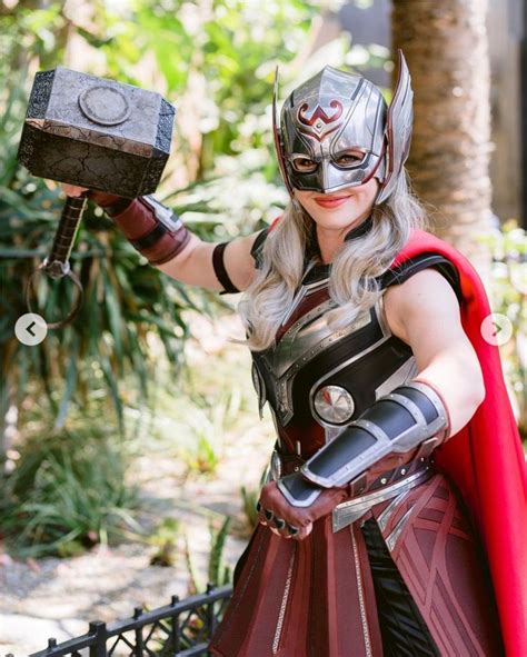 A Woman Dressed As Thor From The Avengers Movie Holding An Iron Block