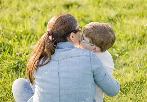 Mignon Fils Baiser Sa Mère Assise Dans Un Champ — Photographie Doble Dphoto © 24512973