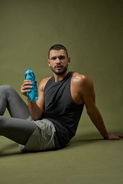 Premium Photo Tired Sportsman Holding Blue Bottle In Hand While