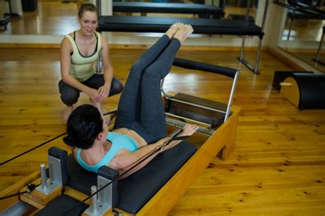 Premium Photo Female Trainer Assisting Woman With Stretching Exercise