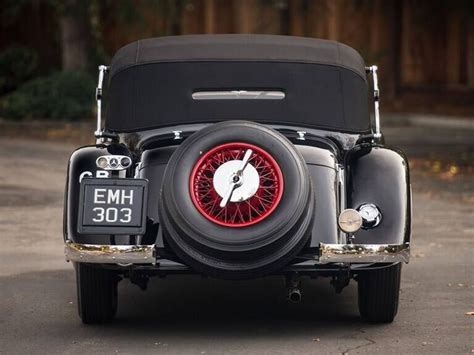 An Antique Car With A Clock On The Front Wheel