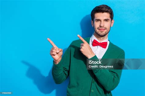 Photo Of Cheerful Positive Guy Dressed Xmas Green Cardigan Pointing Two Fingers Empty Space