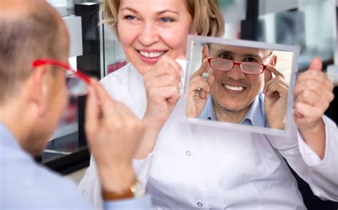 Female Optician Consulting Mature Male Customer About Frames Stock