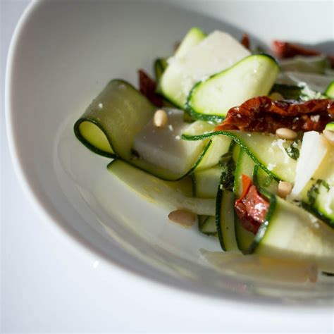 A White Plate Topped With Cucumbers And Other Vegetables On Top Of A Table