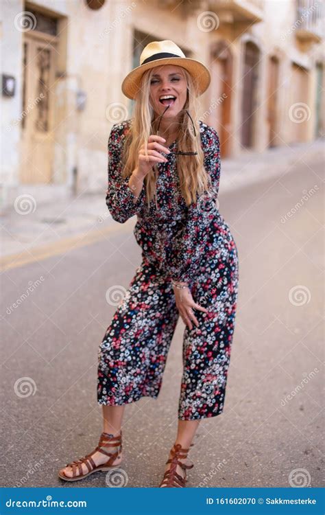Vivacious Blonde Mediterranean Woman Floral Pattern Dress Posing Stock