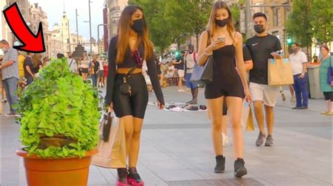 two women walking down the street with shopping bags on their heads and one is looking at her phone