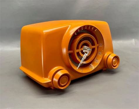 An Orange Clock Is Sitting On A Gray Surface And It Appears To Be Made Out Of Plastic