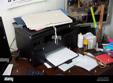 Desk with a printer, papers, computers and office supplies close-up ...