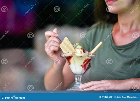 A Delicious Looking Ice Cream Cup With An Out Of Focus Woman Grabbing A