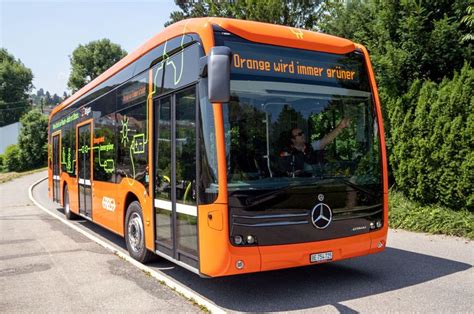 An Orange Bus Is Parked On The Side Of The Road With Trees In The