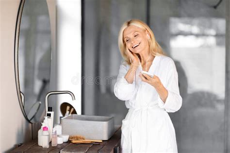 Smiling Mature Woman Wearing White Bathrobe Listening Music On