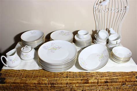 A Wicker Basket With Plates And Cups On It Next To A Bird Cage