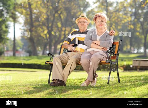 Mature Couple Relaxing Seated On A Bench In Park On A Sunny Day Stock