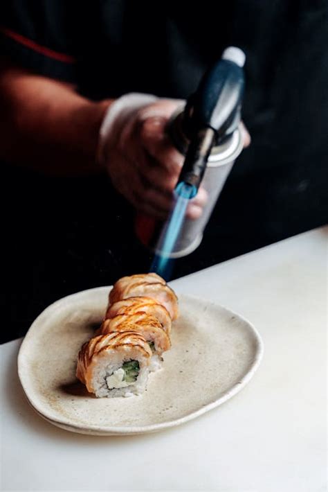 A Chef Using A Blow Torch On Sushi Rolls · Free Stock Photo