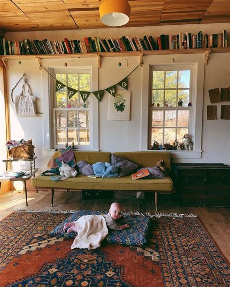 A Baby Is Laying On The Floor In Front Of A Couch And Bookshelf