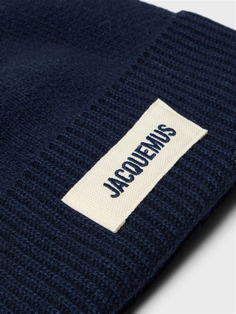 A Close Up View Of The Label On A Navy Blue Beanie With White Stitching