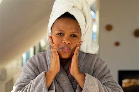 Happy Plus Size African American Woman Wearing Robe Patting Her Face