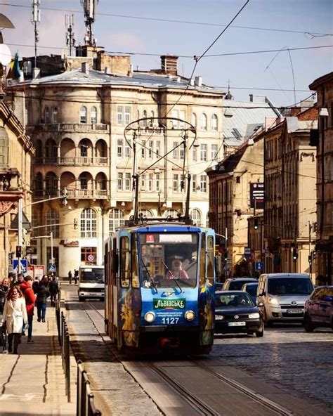 A Blue Trolley Car Traveling Down A Street Next To Tall Buildings And