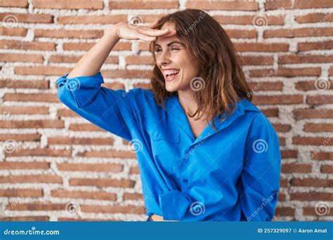 Beautiful Brunette Woman Standing Over Bricks Wall Very Happy And Smiling Looking Far Away With