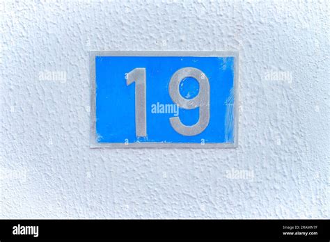 19, number nineteen, blue metal plate on a white wall Stock Photo - Alamy