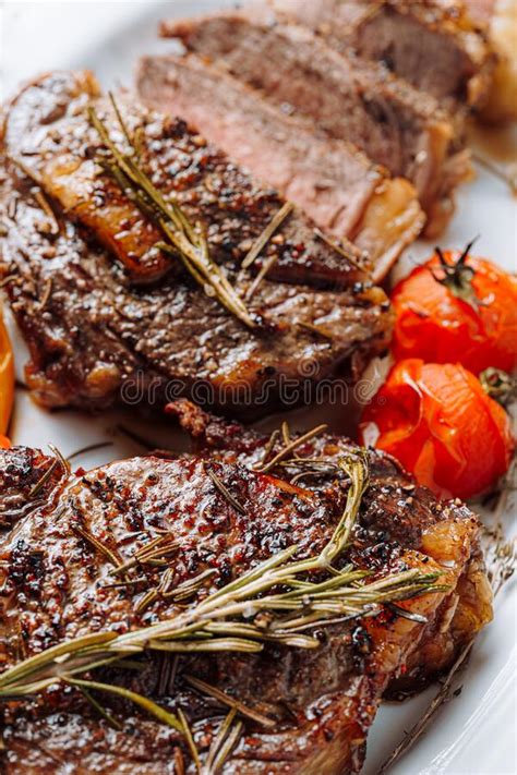 Juicy Well Done Ribeye Steaks On A White Platter On A Dark Wooden