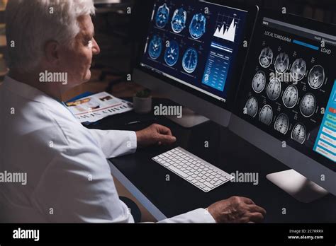 Senior Neurologist With MRI Scan Of Human Head In Clinic Stock Photo