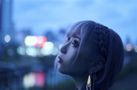 A Woman With Long Hair Standing In Front Of A Cityscape At Night