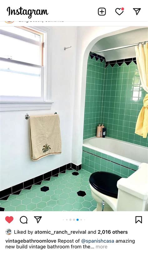 A Bathroom With Green Tile And White Fixtures Including A Black