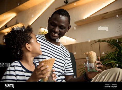 Happy African American Father And Son Eating Ice Cream And Smiling Each