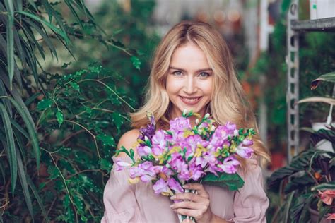 Blonde Jeune Femme Tenant Un Bouquet De Fleurs Mauves En Mains Photo