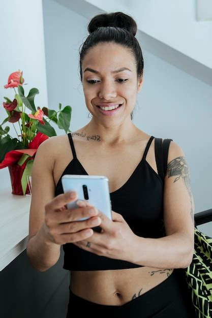 Chica Latina Y Deportiva Usando Su Celular En El Gimnasio Mirando Sus Mensajes O Redes Sociales