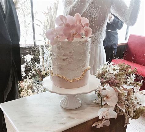 A Wedding Cake With Pink Flowers On Top Sitting On A Table Next To A