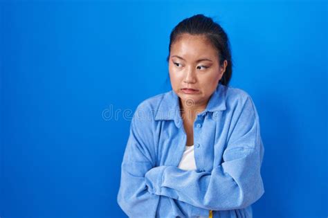 Asian Young Woman Standing Over Blue Background Shaking And Freezing