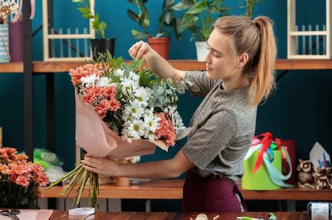 A florista faz um buquê uma jovem adulta segura nas mãos um grande