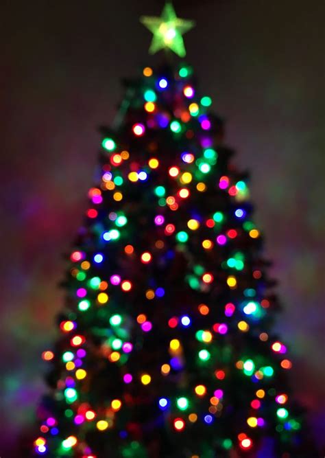 A Brightly Lit Christmas Tree In Front Of A Dark Background With Stars