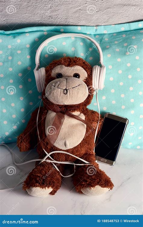 Fluffy Monkey Toy with Headphones and a Smartphone on a Green Blanket Stock Image - Image of ...