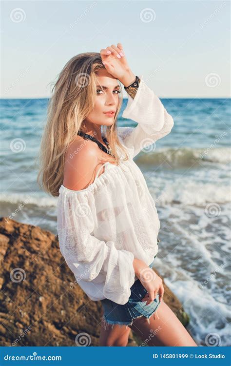 Pretty Blonde Girl With Long Hair Is Posing To The Camera On Sea