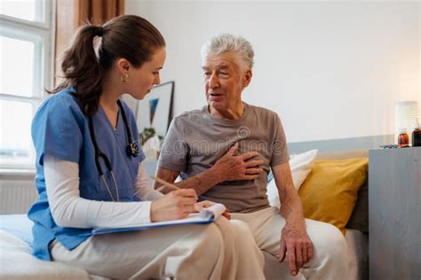 Enfermera Joven Revisando A Ancianos Mayores En Su Casa Imagen De